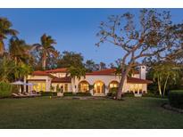 Elegant home exterior with manicured lawn, arched entryway, and a red tile roof at 3930 Red Rock Way, Sarasota, FL 34231