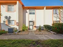 Inviting townhouse exterior featuring light stucco, orange trim, and well-maintained landscaping at 1655 58Th S Ter # 7, St Petersburg, FL 33712