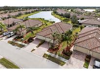 Beautiful aerial view of tile-roofed homes in a well-maintained community with lush landscaping and serene lake views at 20289 Benissimo Dr, Venice, FL 34293