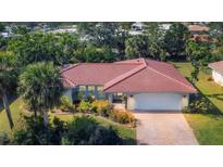 Charming single-story home featuring a red tile roof, lush landscaping, and an attached two-car garage at 395 W Rossetti Dr, Nokomis, FL 34275
