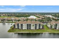 Stunning aerial view of a lakeside condo community with lush landscaping and beautiful water views at 7911 Grand Estuary Trl # 106, Bradenton, FL 34212