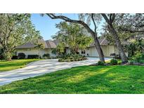 Stunning ranch-style home featuring a circular driveway, lush landscaping, and mature trees providing ample shade at 3178 Dick Wilson Dr, Sarasota, FL 34240