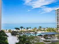 Stunning oceanfront view featuring a swimming pool, lush landscaping and palm trees in an idyllic beach setting at 1211 Gulf Of Mexico Dr # 301, Longboat Key, FL 34228