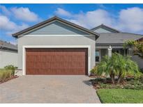 Charming home featuring a well-maintained lawn, a large garage, and a beautiful paver driveway at 12525 Lily Quartz Loop, Parrish, FL 34219