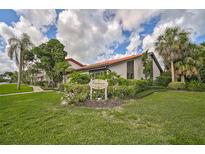 Beautifully landscaped condo with tropical foliage and red tile roof under cloudy blue skies at 800 S Blvd Of Presidents # 12, Sarasota, FL 34236