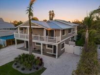 Stunning elevated home with white gravel landscaping, a metal roof, and wraparound porch at 203 72Nd St, Holmes Beach, FL 34217