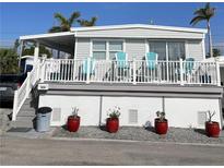 Charming elevated home featuring a covered porch with bright blue chairs, perfect for relaxing outdoors at 2601 Gulf N Dr # 528, Bradenton Beach, FL 34217