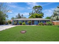 Charming single-story home with a well-manicured lawn, lush landscaping, and a blue exterior at 3902 11Th W Ave, Bradenton, FL 34205
