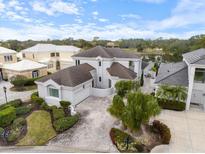Stunning aerial view of a luxurious two-story home with a tile roof, paver driveway, and lush landscaping, with lake view at 7716 Club Ln, Sarasota, FL 34238