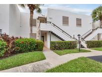 Exterior view of a two-story home with green foliage and stairs leading to an upper-level entrance at 542 Lakeside Dr # 542, Bradenton, FL 34210