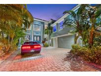 Stunning two-story home featuring lush tropical landscaping, a paver driveway, and a three-car garage at 1215 Acappella Ln, Apollo Beach, FL 33572