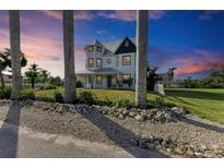 Beautiful two-story home with unique architectural details, lush landscaping, and a pristine lawn at 1825 Bayshore Dr, Terra Ceia, FL 34250