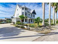 Charming two-story home with a metal roof, lush landscaping and a well-manicured lawn at 1825 Bayshore Dr, Terra Ceia, FL 34250