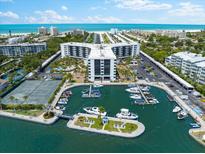 Stunning aerial view of a waterfront condo community with a marina, tennis courts, and beautiful coastal scenery at 5855 Midnight Pass Rd # 311, Sarasota, FL 34242