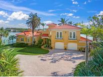 Stunning Mediterranean-style home with a red tile roof, lush landscaping, and paver driveway leading to a two-car garage at 929 Casey Cove Dr, Nokomis, FL 34275