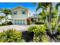 Charming two-story home with lush landscaping and a welcoming front entrance with decorative garage door at 213 84Th St, Holmes Beach, FL 34217