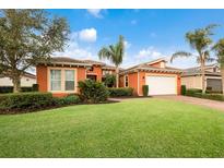 Charming orange home featuring a well-manicured lawn, mature trees, and a convenient two-car garage at 5203 Lake Overlook Ave, Bradenton, FL 34208