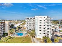 Bright, airy, white condo building with a community pool and tropical landscaping under a sunny blue sky at 5830 Midnight Pass Rd # 502, Sarasota, FL 34242