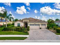 Charming single-story home featuring a three-car garage, terracotta tile roof, and lush tropical landscaping at 6630 Horned Owl Pl, Sarasota, FL 34241