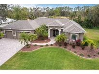 Beautiful single-story home featuring a three-car garage, well-manicured lawn, and lush tropical landscaping at 3826 E 155Th E Ave, Parrish, FL 34219