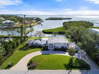 Stunning waterfront home featuring lush landscaping, circular driveway, and beautiful bay views at 7056 Hawks Harbor Cir, Bradenton, FL 34207