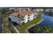 Aerial view of light green building with screened balconies, tile roof and pond view at 1000 San Lino Cir # 1032, Venice, FL 34292