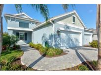 Charming single-Gathering home showcasing paver walkway and lush landscaping leading to a two-car garage at 2722 Sapphire Blue Ln, Bradenton, FL 34211