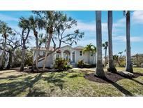 Beautiful exterior view of a single-Gathering home with mature trees, lush landscaping, and a well-manicured lawn at 3540 Bayou Cir, Longboat Key, FL 34228