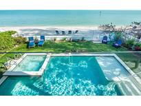 Aerial view of a backyard pool and hot tub with beach access and lounge seating at 915 N Shore Dr, Anna Maria, FL 34216