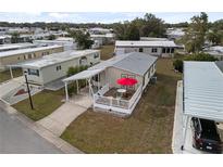 Charming mobile home featuring a cozy outdoor deck with an umbrella, covered parking and a well-maintained yard at 5539 Holiday Park Blvd, North Port, FL 34287