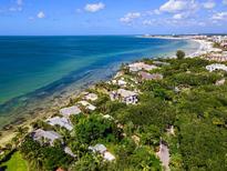 Stunning aerial view showcasing beachfront homes along the coastline with turquoise waters and lush greenery at 7314 Point Of Rocks Rd, Sarasota, FL 34242