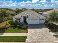 Beautiful home featuring a well-manicured lawn, lush landscaping, and a spacious three-car garage at 8261 Grande Shores Dr, Sarasota, FL 34240