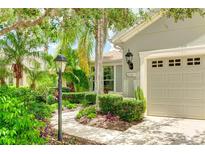 Charming home featuring a well-manicured front yard with lush tropical landscaping and a private two-car garage at 11662 Old Cypress Cv, Parrish, FL 34219