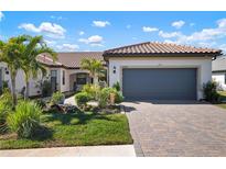 Beautiful single-story home with lush landscaping, brick driveway, and tile roof at 14369 Eagle Branch Dr, Nokomis, FL 34275