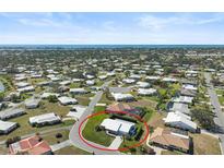 Wide aerial shot showcasing a community of single-Gathering homes with manicured lawns and a glimpse of the ocean in the distance at 308 Matisse E Cir, Nokomis, FL 34275