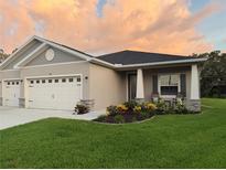 Charming single-story home featuring a two-car garage, manicured lawn, and colorful flower beds at 6614 162Nd E Pl, Parrish, FL 34219