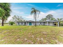 Charming single-story home featuring a spacious front yard, complemented by lush greenery and a welcoming teal-colored front door at 800 Riviera St, Venice, FL 34285
