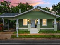 Charming green home with white columns and a cozy front porch enhanced by lush landscaping at 1010 E Lake Ave, Tampa, FL 33605