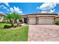 Well-manicured home exterior with a brick driveway, lush green lawn, and charming landscaping at 20686 Valprato Ct, Venice, FL 34293