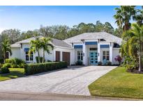 Bright exterior showcasing a pristine white facade, vibrant blue accents and a paver driveway at 3407 155Th E Ave, Parrish, FL 34219
