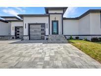 Modern home featuring a textured driveway, minimalist landscaping, and stylish garage doors with matching front door at 1327 Wesley Dr, Punta Gorda, FL 33950
