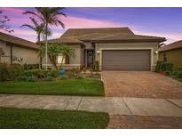 Charming one-story home with a brick driveway, two-car garage, and lush landscaping at 13925 Miranese St, Venice, FL 34293