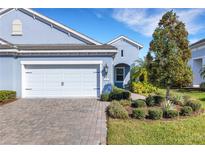 Charming blue single-Gathering home showcasing a well-maintained lawn and a two-car garage with brick driveway at 3325 Azurite Way, Bradenton, FL 34211
