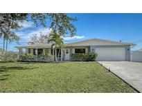 Charming single-story home with a well-manicured lawn, lush landscaping, and an attached two-car garage at 603 Barnes Pkwy, Nokomis, FL 34275