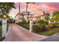 Stunning waterfront home with lush landscaping, a brick driveway, and a picturesque view of the colorful sunset at 1023 Tocobaga Ln, Sarasota, FL 34236