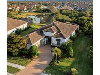 Stunning aerial view of a modern home with a tile roof, lush landscaping, and a serene pond at 5341 Greenbrook Dr, Sarasota, FL 34238