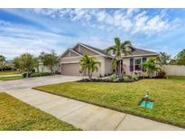 Charming one-story home boasts a paver driveway, well-manicured lawn, and lush landscaping with tropical plants at 6428 Devesta Loop, Palmetto, FL 34221
