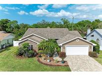 Charming home with a brick-accented facade, lush landscaping, and a paved driveway leading to a two-car garage at 5708 39Th Street E Cir, Bradenton, FL 34203