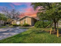 Charming single-story home with a well-manicured lawn and mature trees under a colorful sky at sunset at 3443 Tallywood Cir # 7061, Sarasota, FL 34237