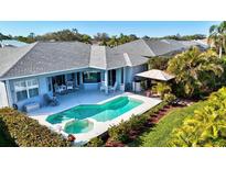 Backyard pool with a spa, surrounding landscaping, outdoor dining, and a grilling cabana at 7453 Featherstone Blvd, Sarasota, FL 34238